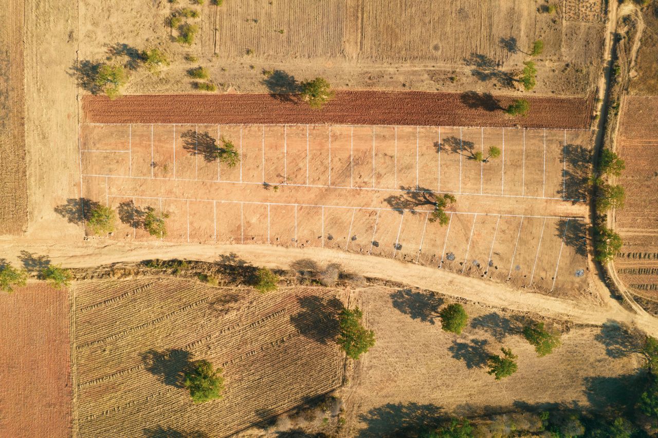 Drone shot of a rural farm landscape with fields and trees in summer.