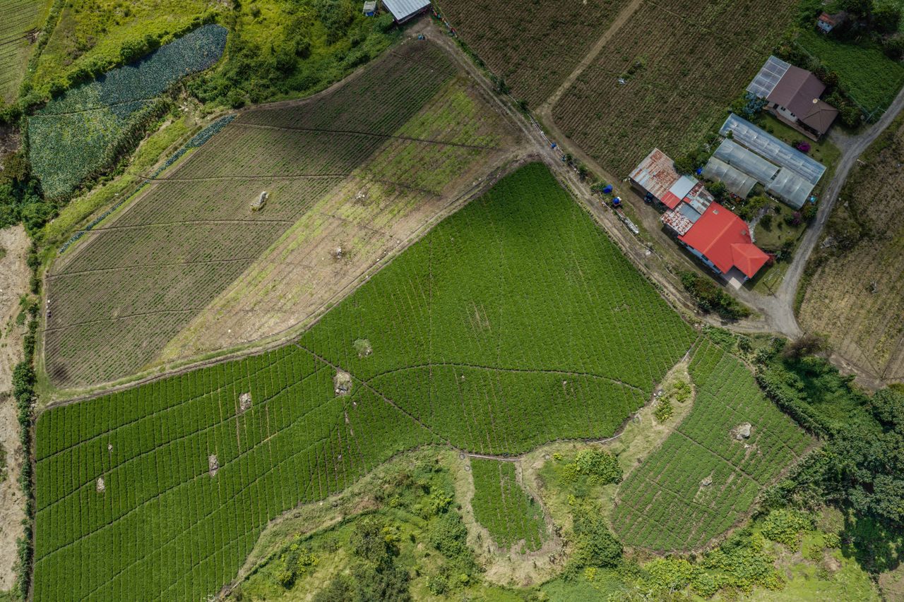 A stunning aerial shot of lush farmland with red roof buildings in the countryside.
